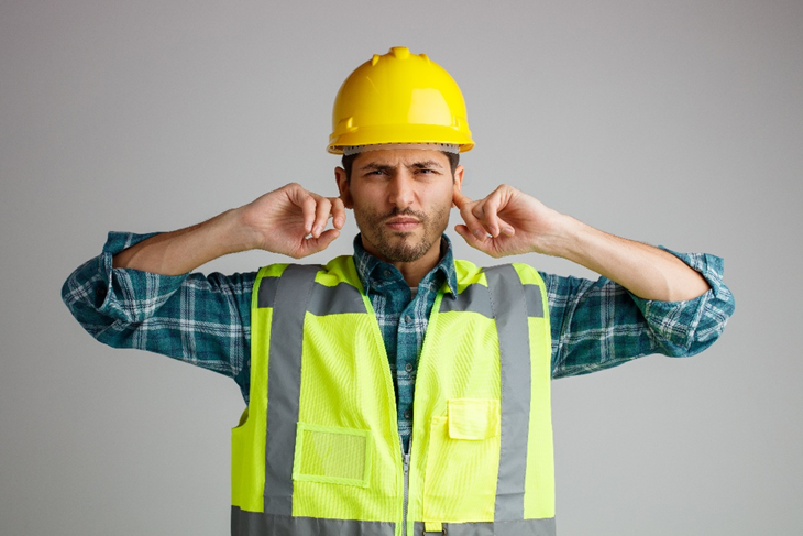 Imagem de um trabalhador de obras com incômodo ou ouvido devido a ruído alto ou trauma acústico