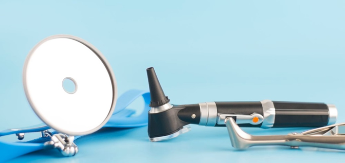 Foto de instrumentos usados no exame físico do otorrino: espelho frontal, otoscópio e espéculo nasal