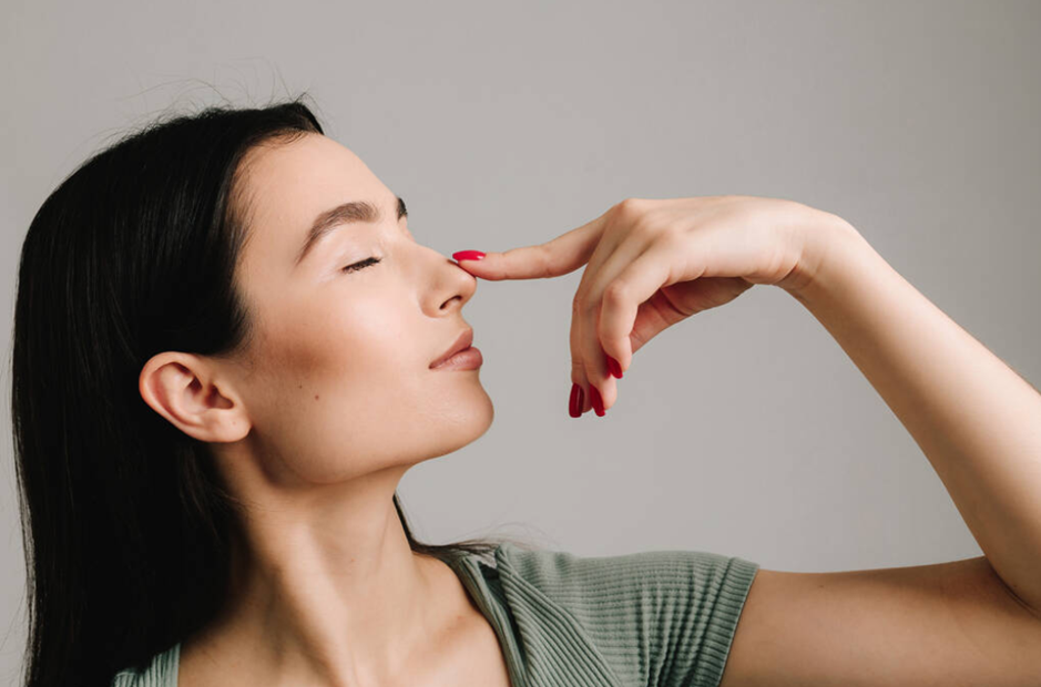 Mulher tocando a ponta do próprio nariz, representando o desejo de realizar uma rinoplastia