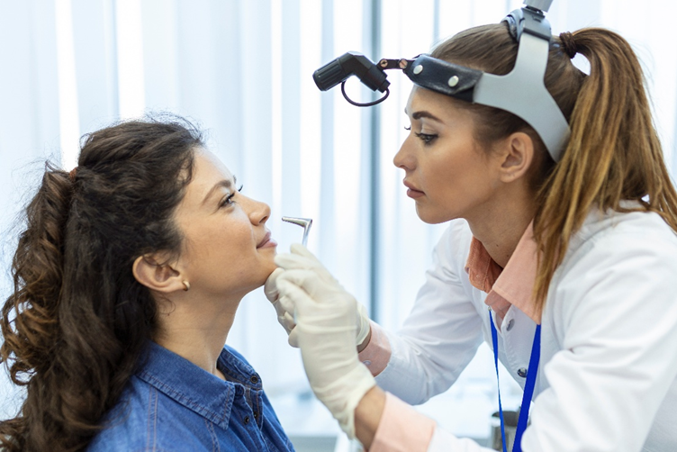 Otorrinolaringologista examinando uma paciente e realizando a rinoscopia anterior